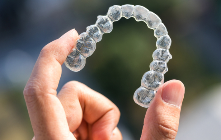 a hand holding an invisalign clear retainer