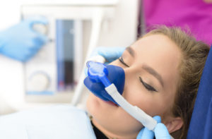 Woman with a mask over her nose and eyes closed undergoing sedation dentistry