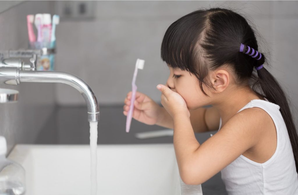 young girl brushing her teeth at the bathroom sink