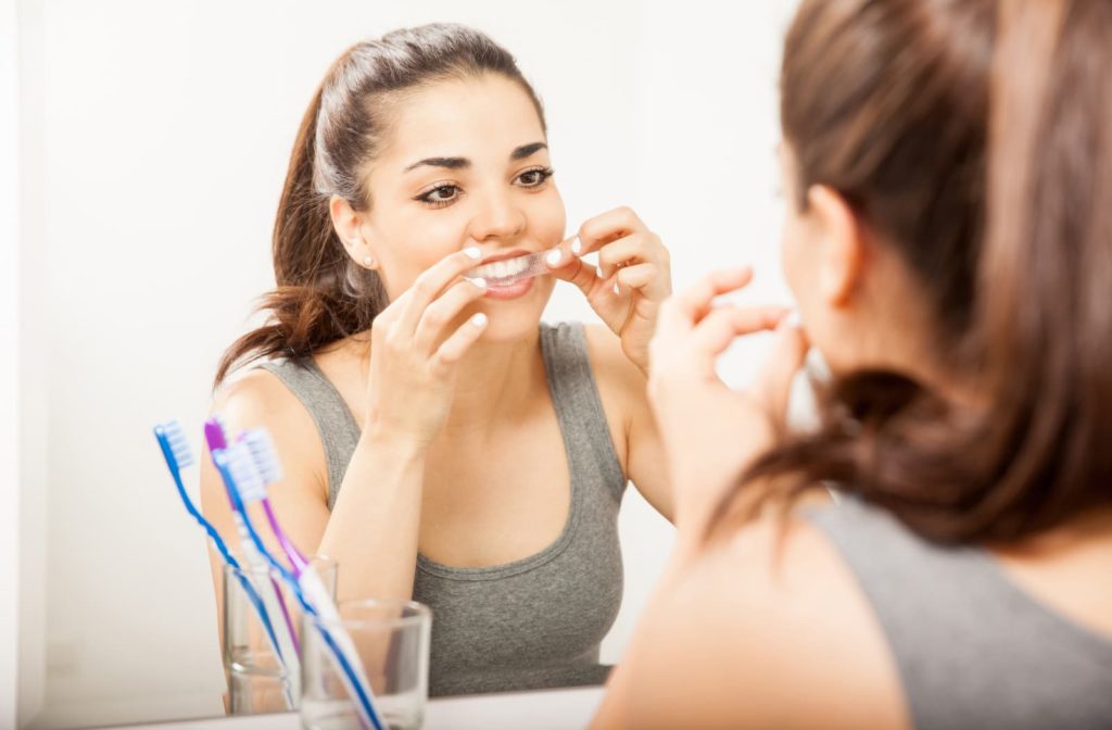 woman using whitening strips to whiten her teeth at home