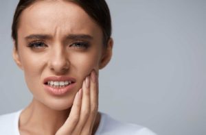 Woman touching her jaw because of dental pain caused by dental disease