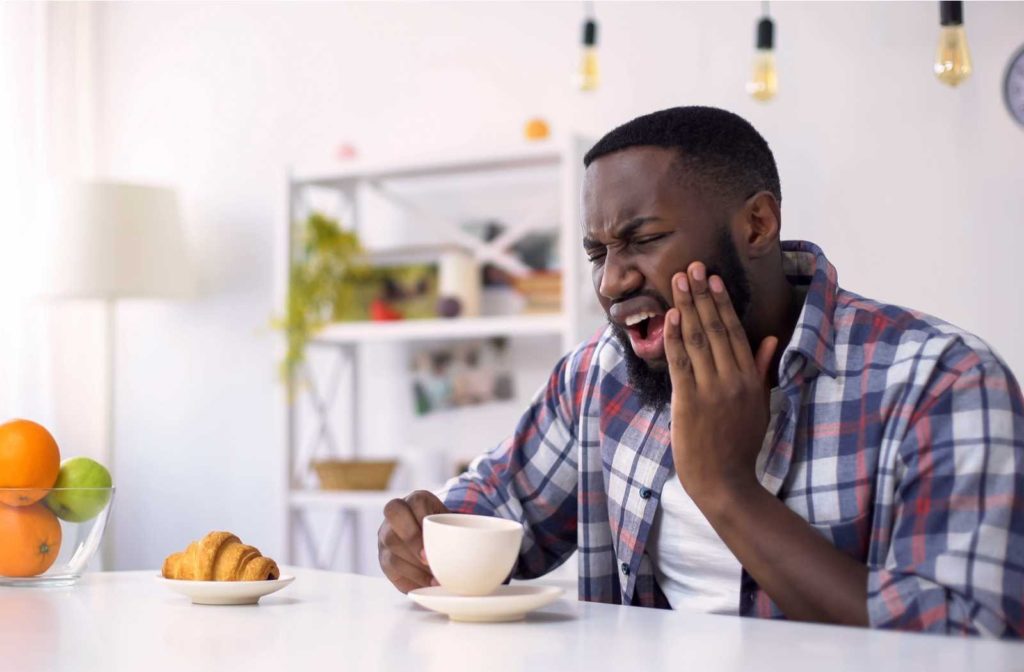 man in flannel shirt and white background holding jaw in pain