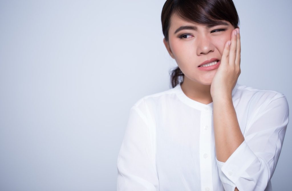Woman clutching her cheek in pain from a toothache