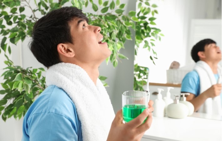 Man swishing with green mouthwash to improve oral hygiene