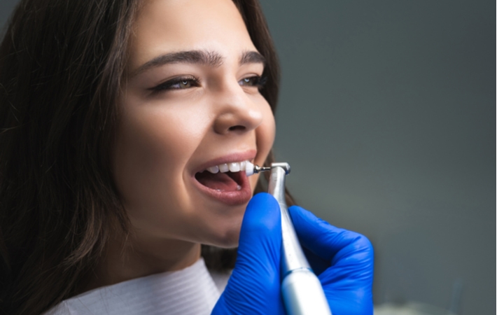 A dentist using a dental brush to polish a female patients teeth while she's at her regular dental cleaning