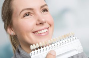 A woman smiling with a variety of veneers placed in front of her face