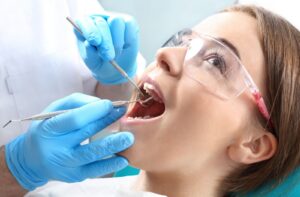 A woman sits back in the chair at the dentist while a dentist prepares for a root canal procedure
